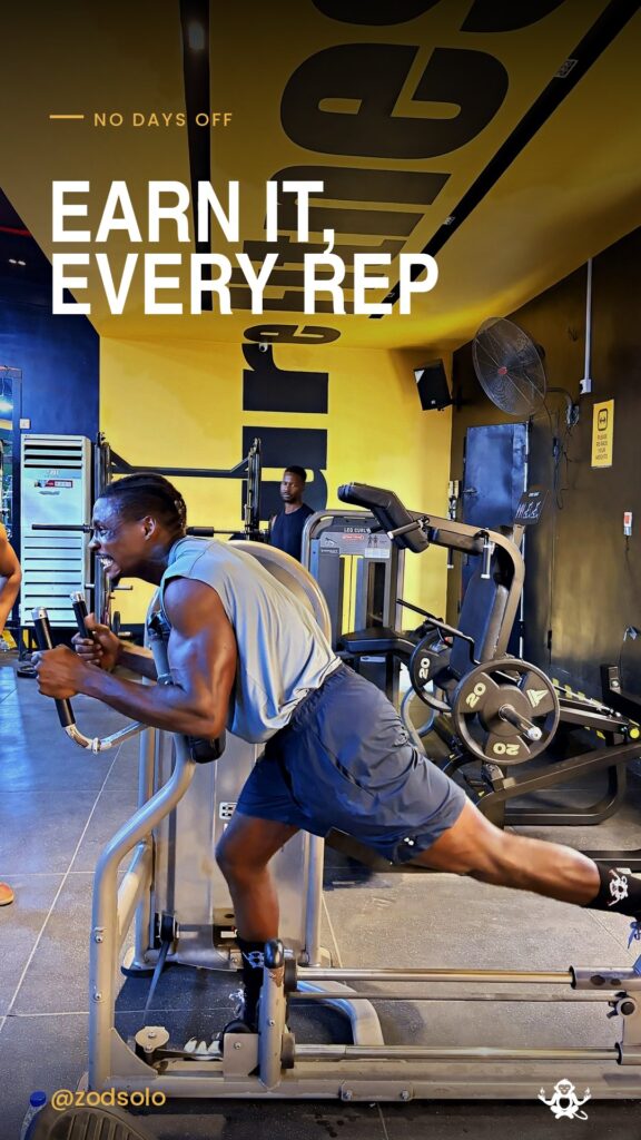 Zodsolo training in the gym, in an AfroAlien Fit "Earn it, every rep" graphic.