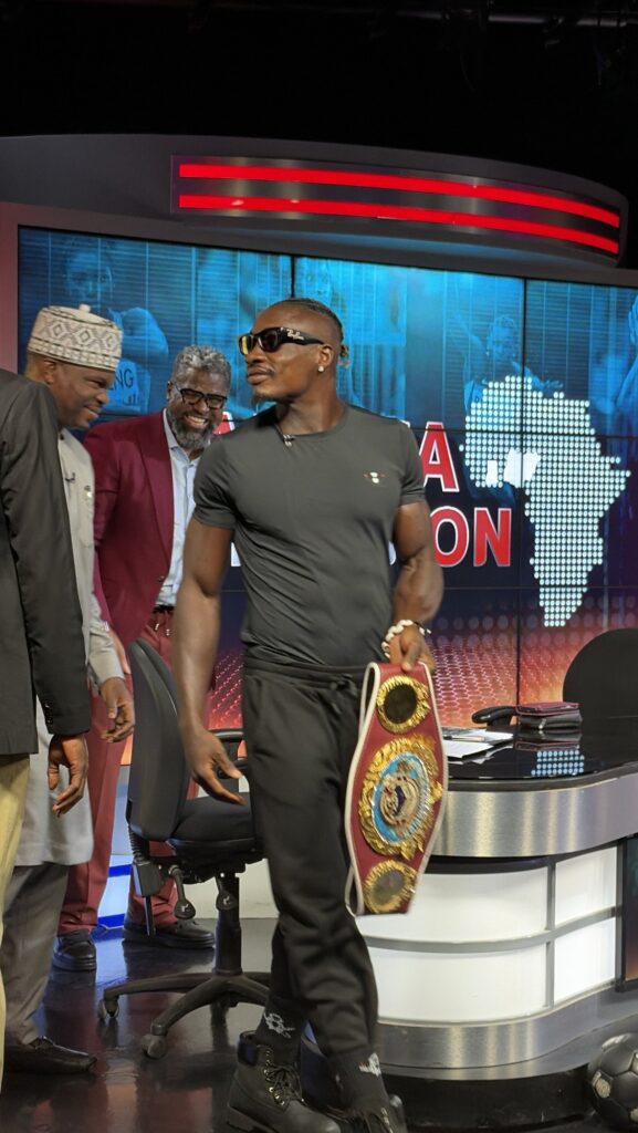 Zodsolo carries his WBO Africa title belt in a television studio.