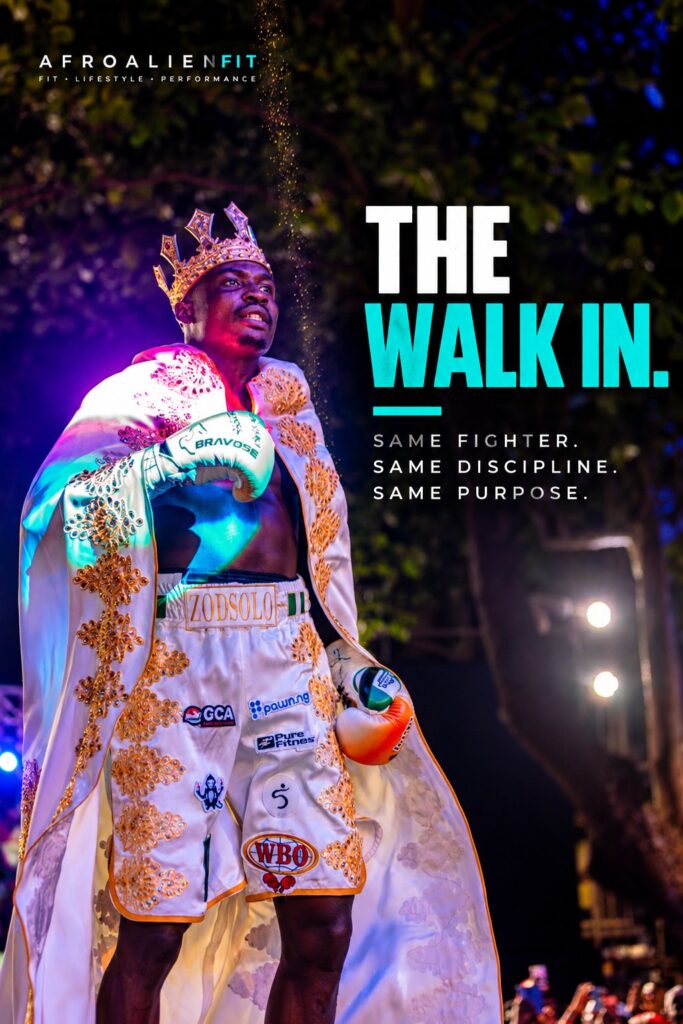 Zodsolo walks to the ring wearing a crown and an embellished white robe, in an AfroAlien Fit "The Walk In" graphic.